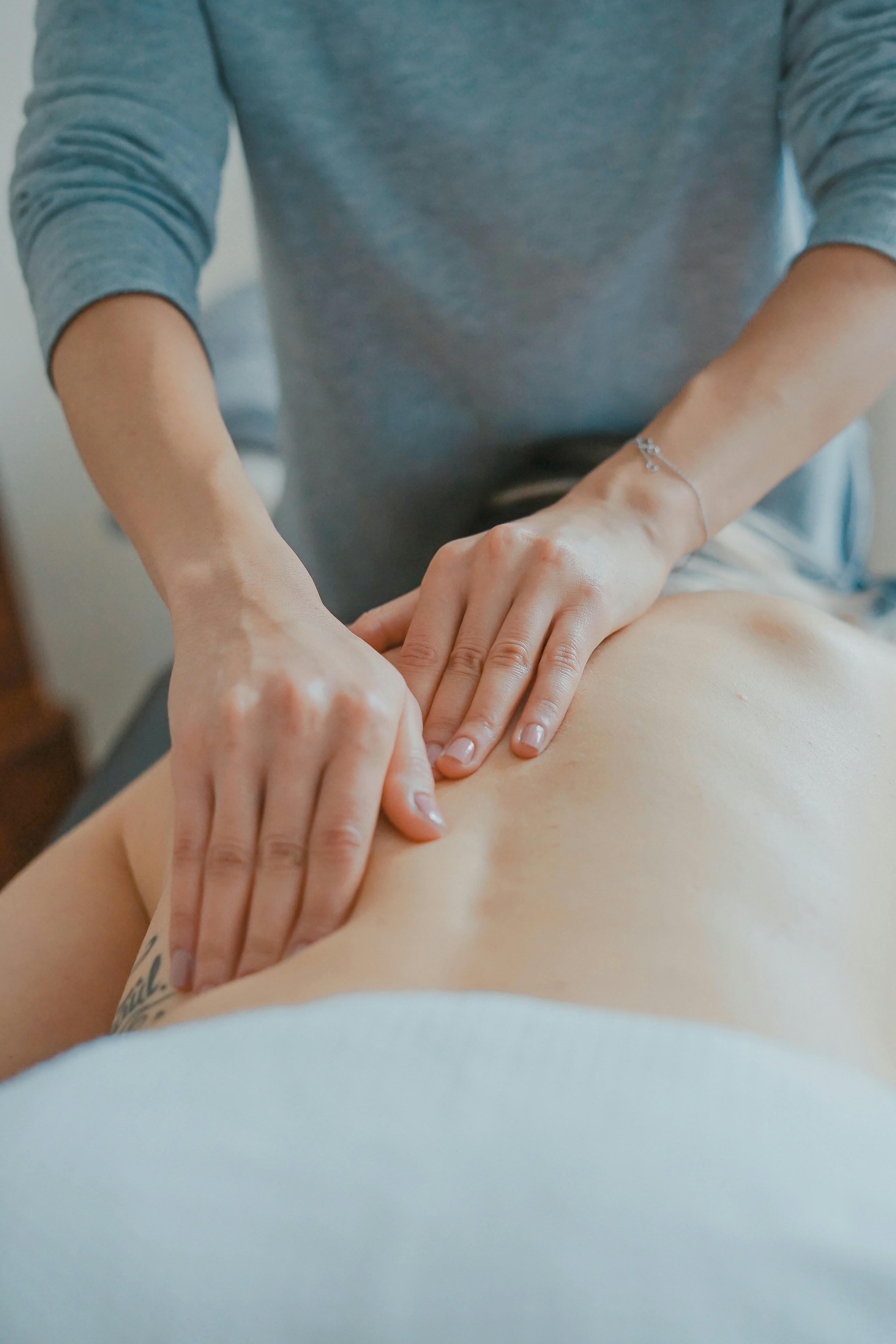 Licensed massage therapist relieving back pain and muscle tension at home