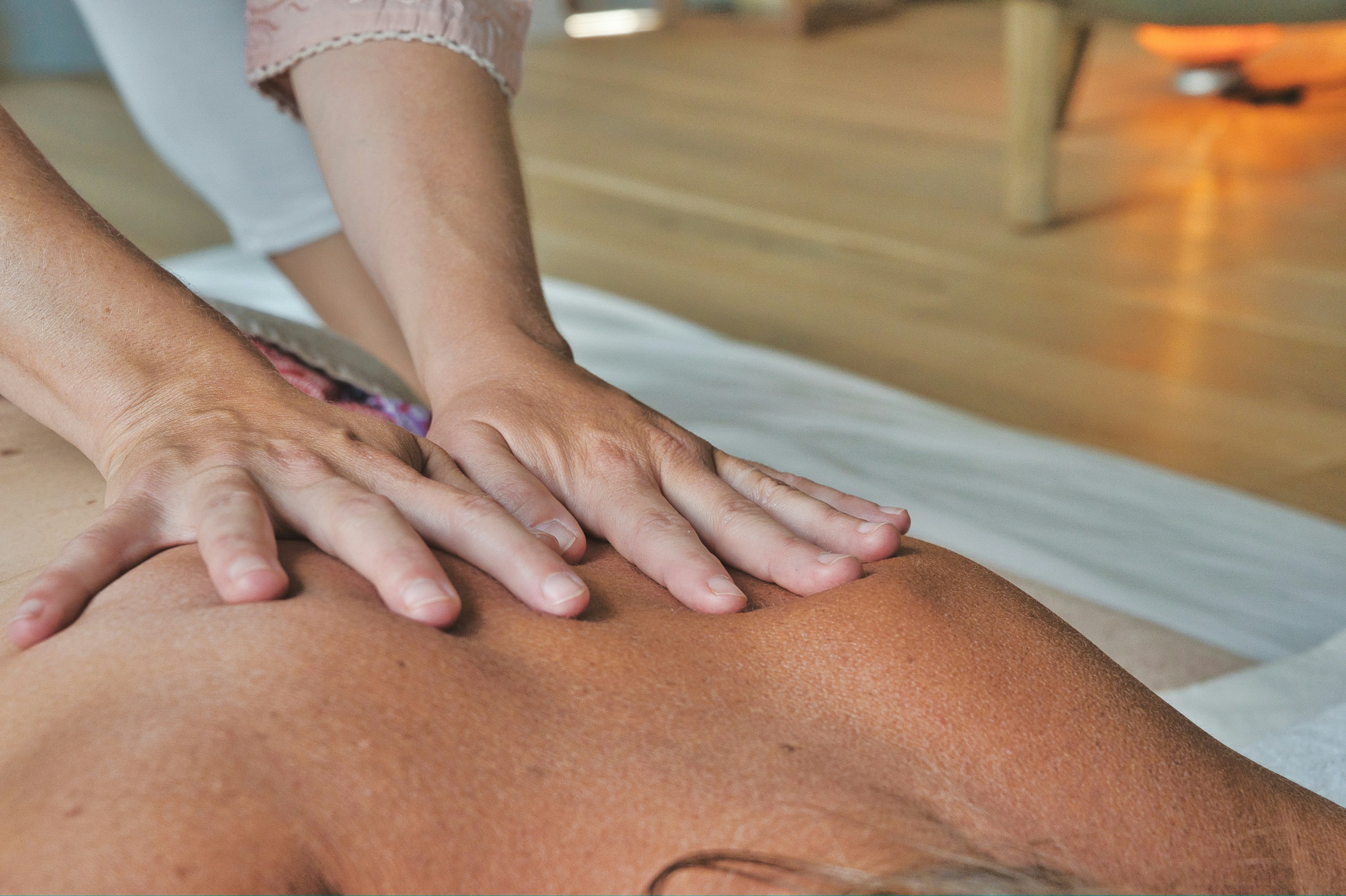 Licensed massage therapist relieving back pain and muscle tension at home